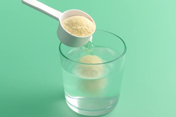 Whey protein em pó sendo misturado em um copo d'água